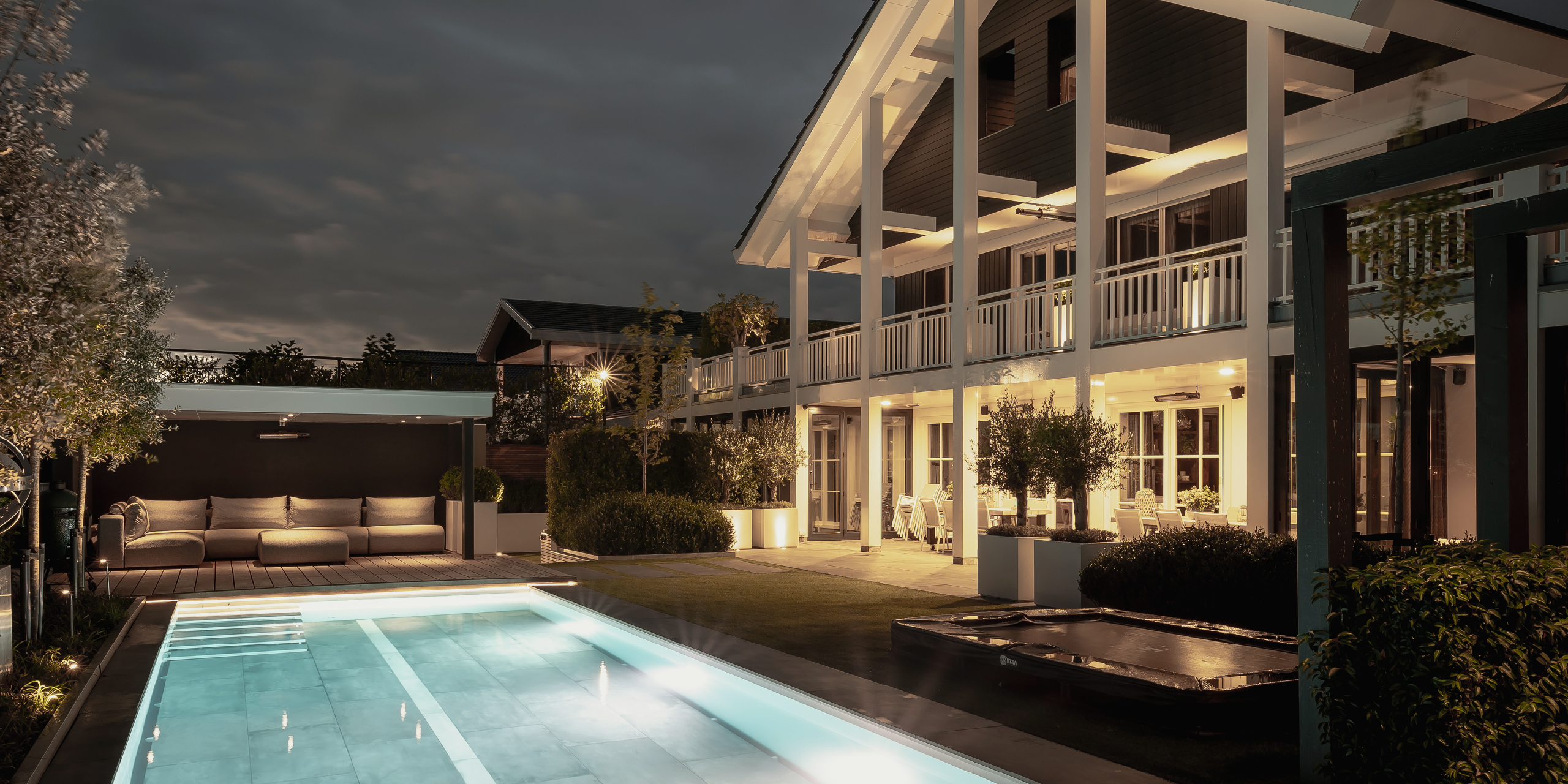 Buytengewoon wellnesstuin in Leeuwarden met zwembad, vlonder, loungehoek, veranda, trampoline en buitenverlichting.