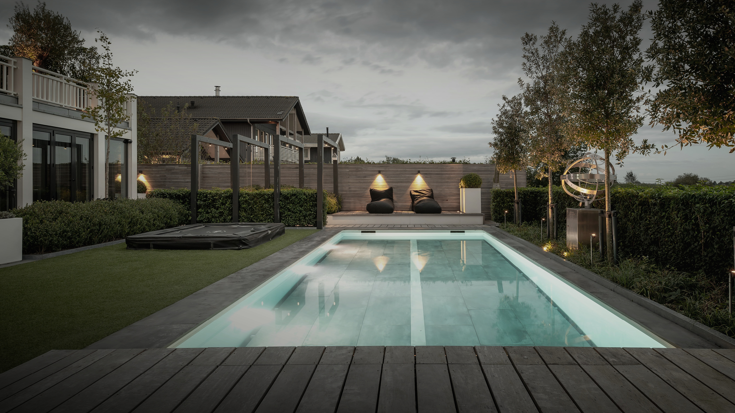 Buytengewoon wellnesstuin in Leeuwarden met trampoline, zwembad, buitenverlichting, liguster, pergola's en kunstgras.
