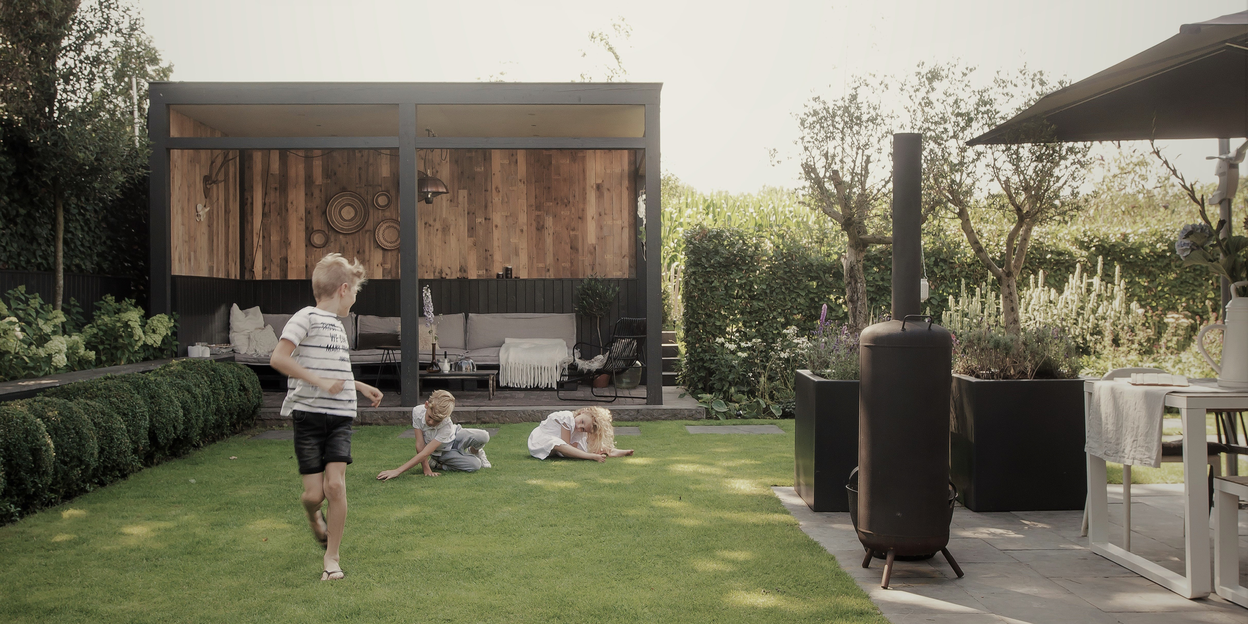 Buytengewoon leeftuin in Elspeet met gazon, terras, veranda, plantvak en buxusbollen.