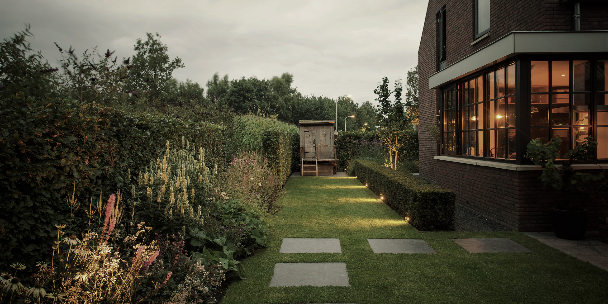 Buytengewoon leeftuin in Elspeet met bloemen, plantvak, gazon, staptegels, taxushaag en speelhuisje.